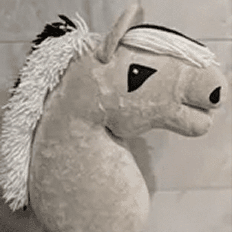 A plush toy horse with a beige body, white mane, and black eyes, shown against a neutral background.