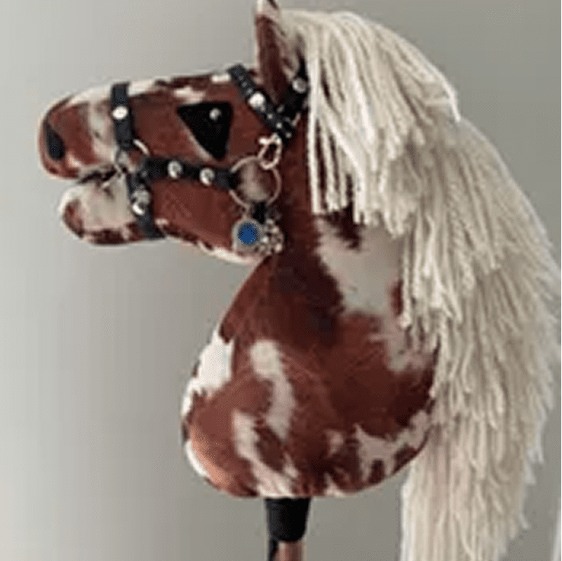 Toy hobby horse with a brown and white pattern, black bridle, and white yarn mane.