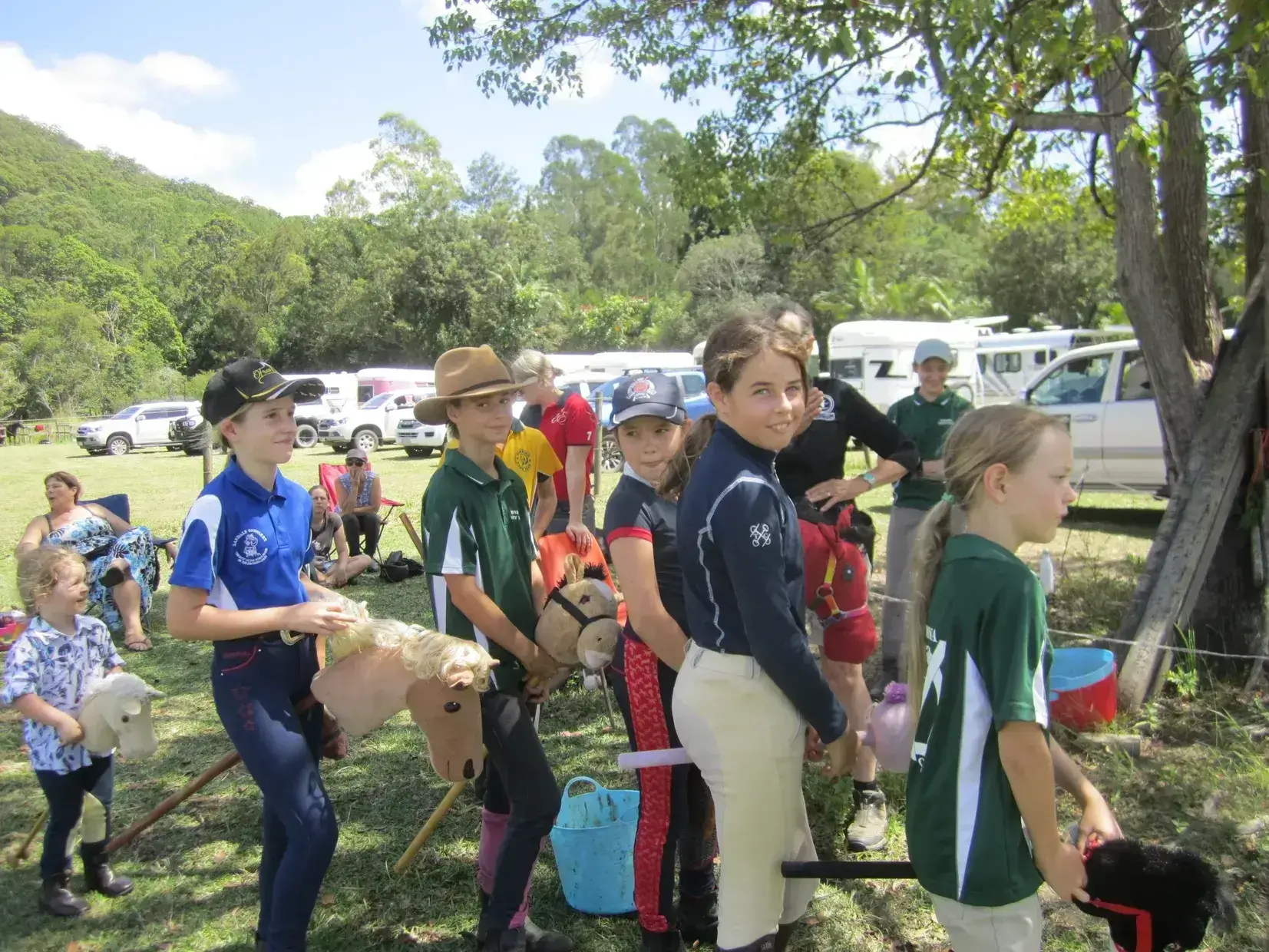 Children lined up outdoors, holding fishing rods.