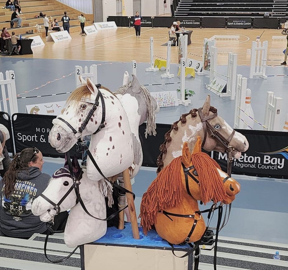 Toy horses displayed at indoor sports event.