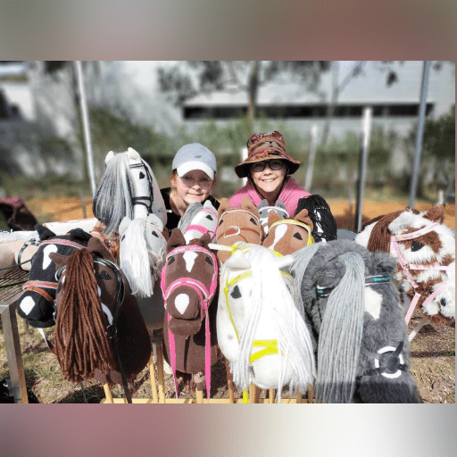 Two children riding hobby horses with joyful expressions outdoors.